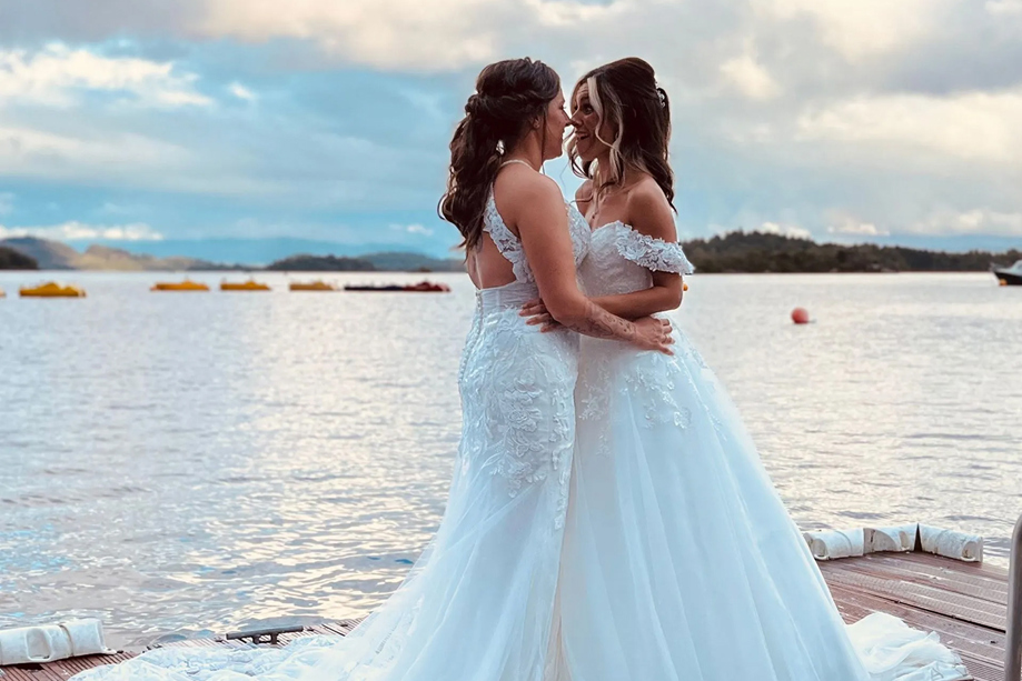 Two brides embrace on boardwalk